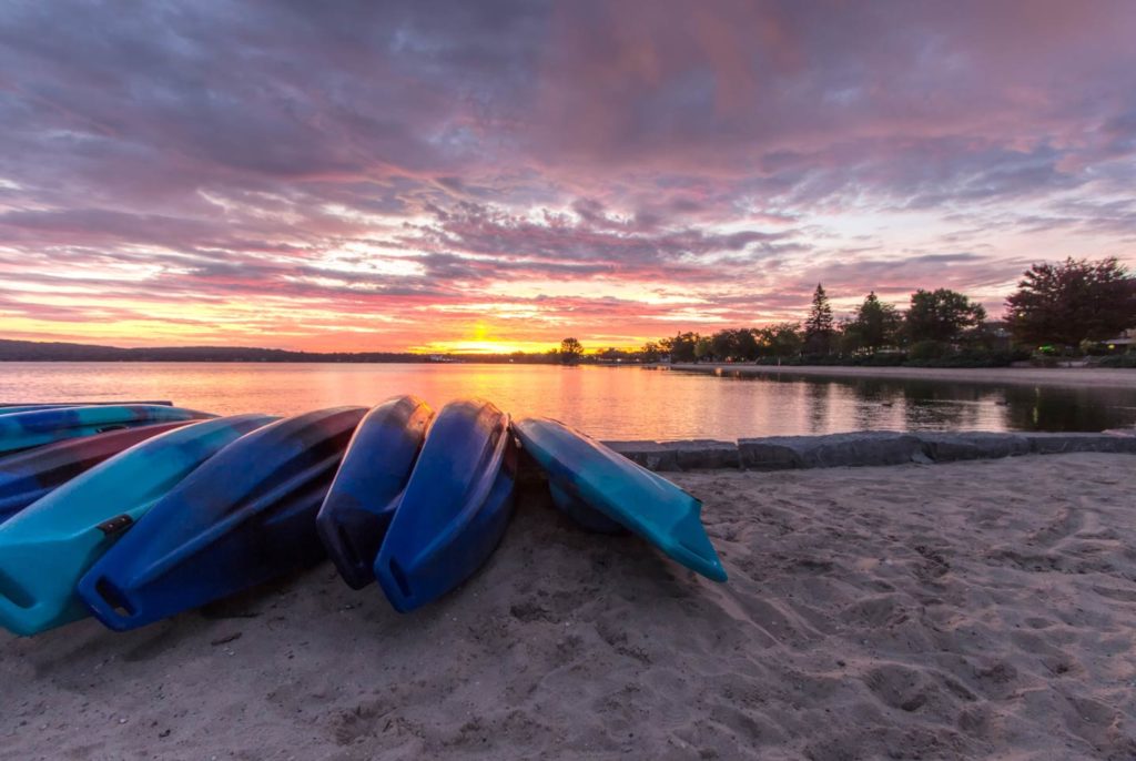 Kayaks resting on the shore of a lake in Traverse City at sunset