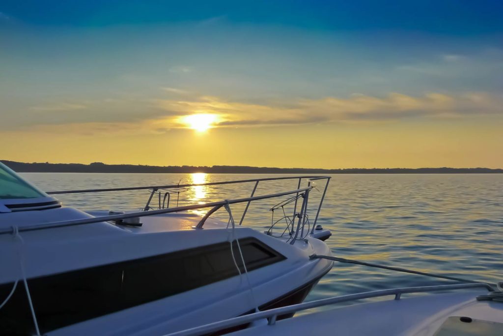 A view out onto Grand Traverse Bay from a charter boat with the boat in the foreground and the sun setting in the distance