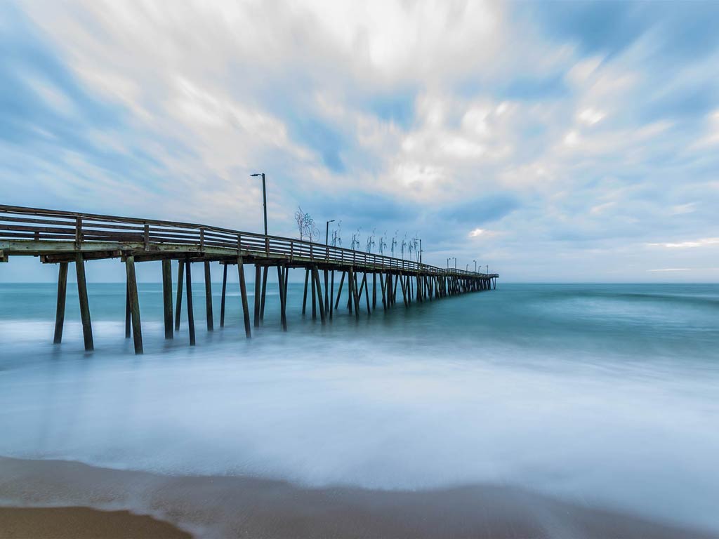 A photo featuring a wooden pier extending well into the Chesapeake Bay as seen on a early morning 