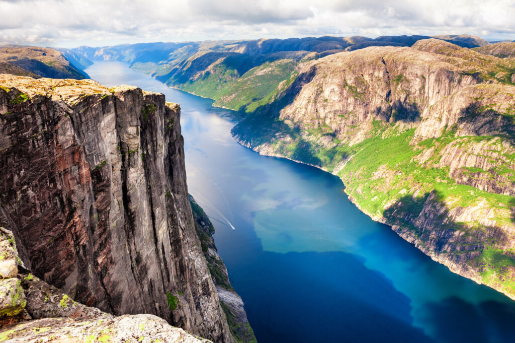 Blick &uuml;ber den Lysefjord bei Stavangar in Norwegen. Links eine Felsklippe, rechts im Hintergrund sind Berge.