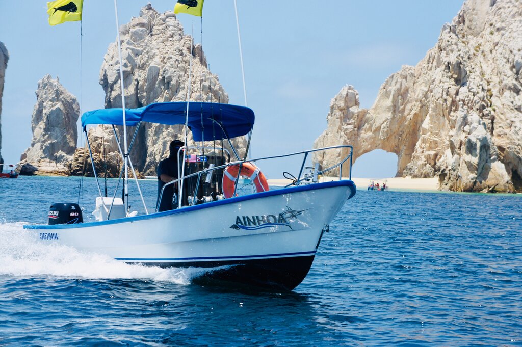 A charter fishing boat with the famous arch of Cabo San Lucas in the background
