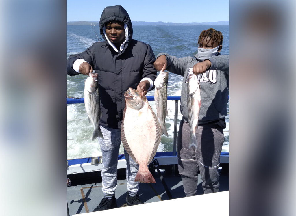 two young anglers, each holding two fish on a fishing boat near San Francisco