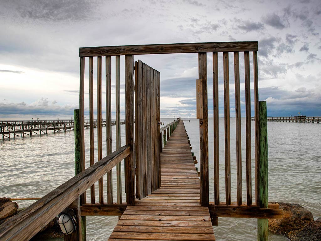 A photo featuring a wooden entrance and a wooden pier near Port Mansfield in Texas where you can fish for Snook