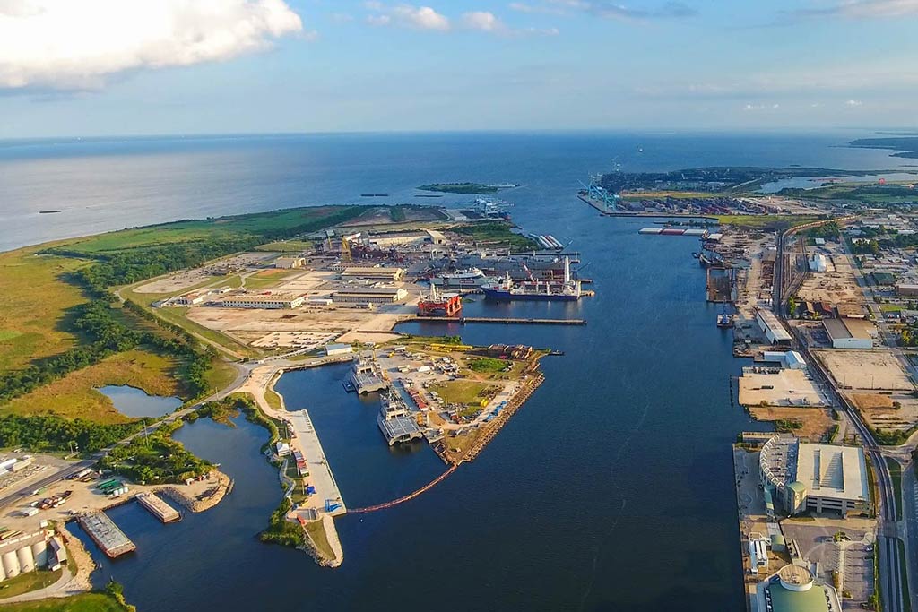 An aerial view of the Port of Mobile, Alabama, with the bay and inlet dominating the centre of the image, while the Gulf of Mexico is visible in the distance