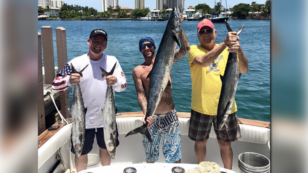 Captain Rudy Neumann on the boat with customers, each holding fish in their hands