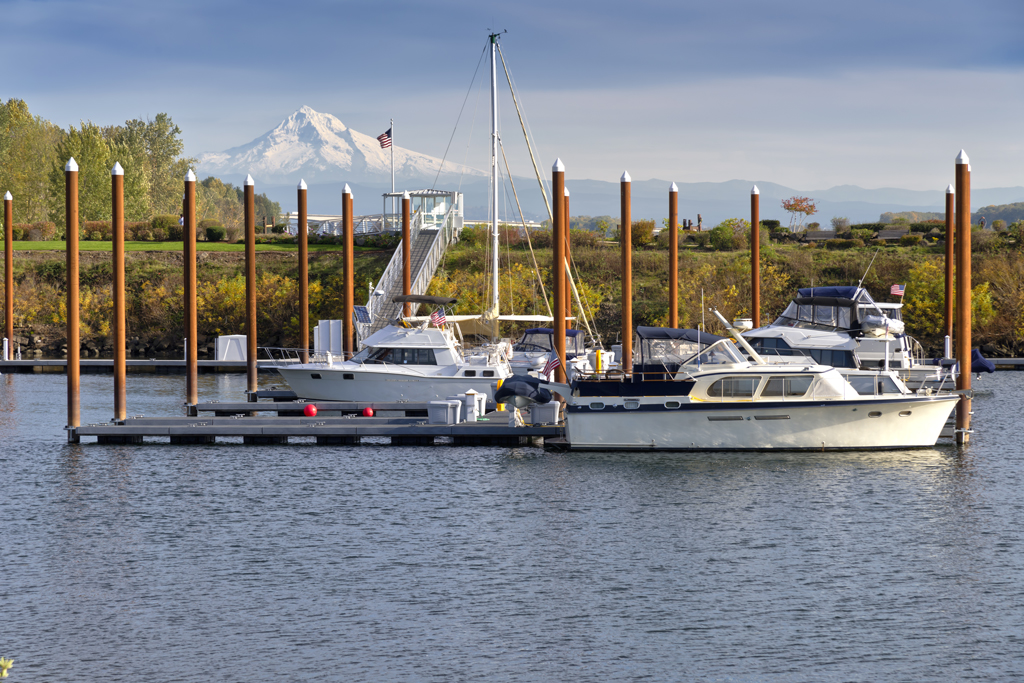 Charter boats docked in a marina along the Columbia River with mountains in the background