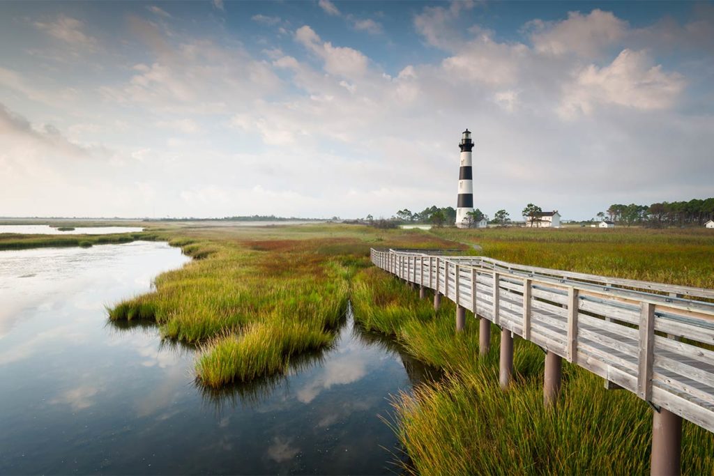 A lighthouse on an island in the Outer Banks stands out from the backcountry