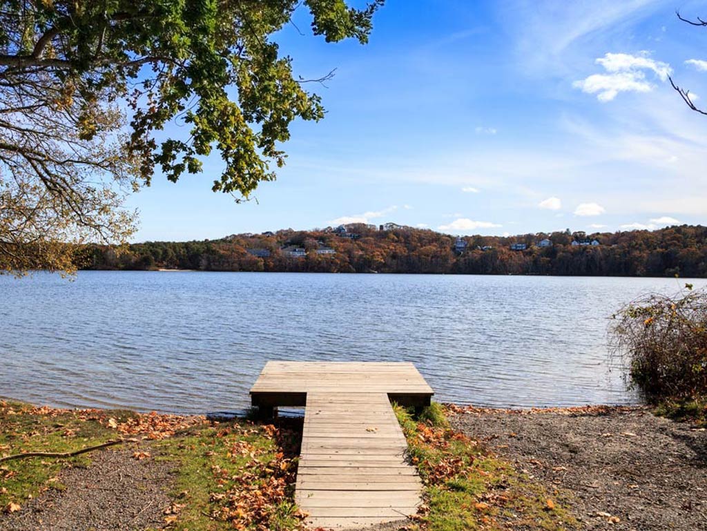A photo of a small dock on Scargo Lake, one of the top freshwater fishing spots in Massachusetts taken on a bright spring day