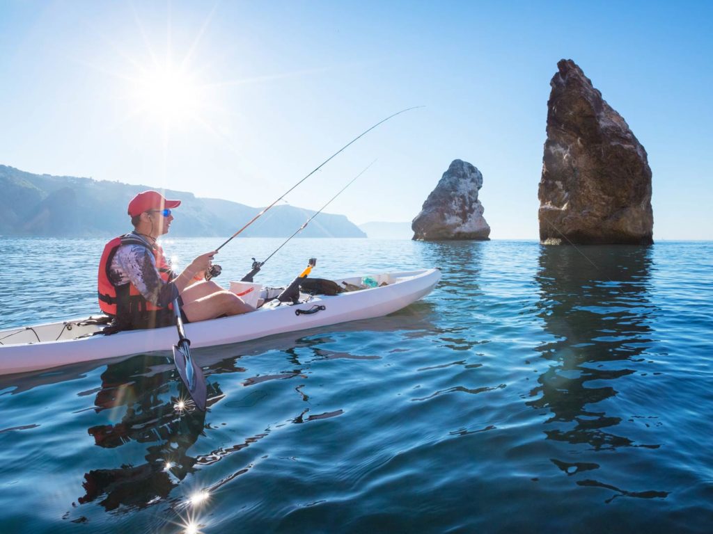 A man fishing from a kayak in tropical waters