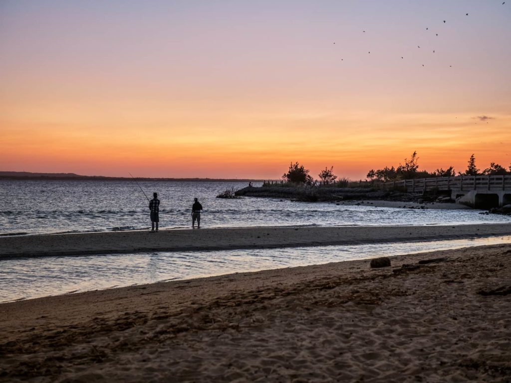 Two men fishing on the beach in Sandy Hook at sunset