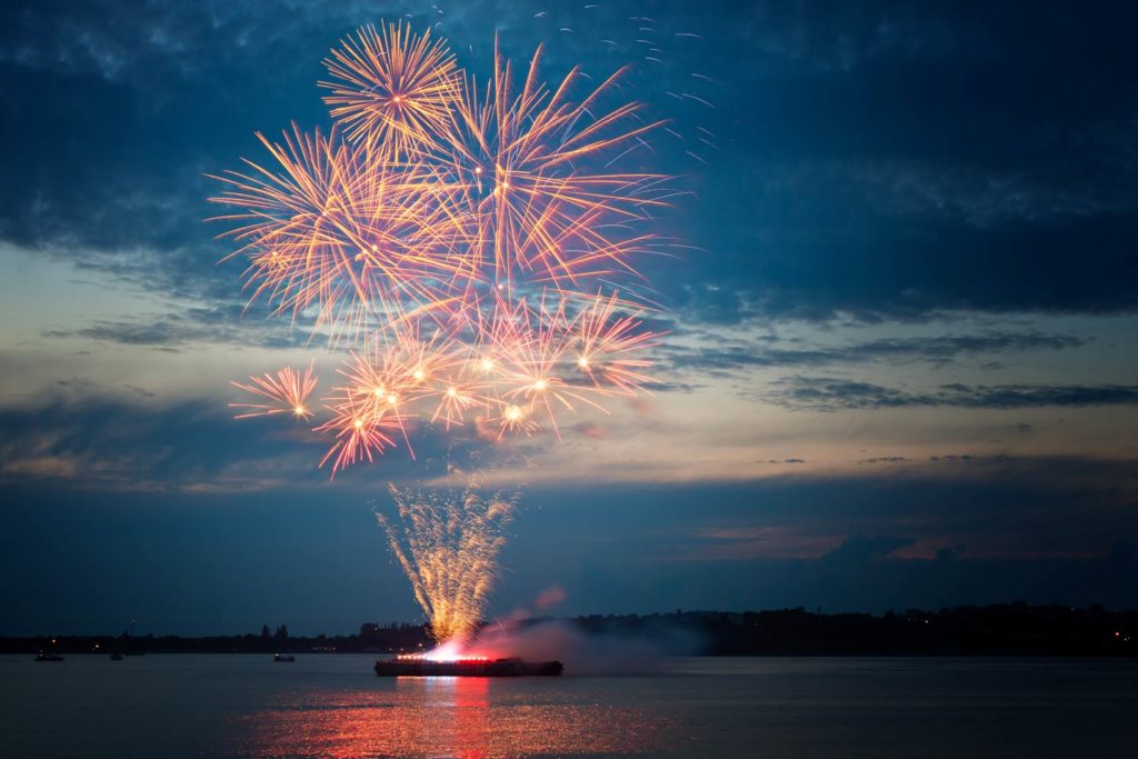 Fireworks over the water in the night sky.