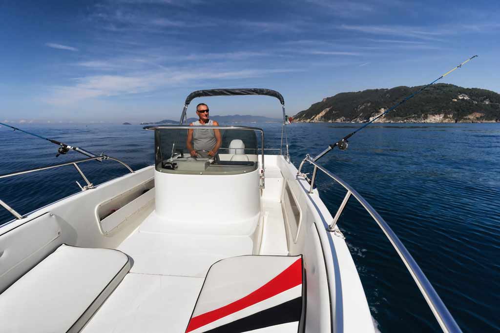 A charter captain operating his boat with blue skies and water in the background