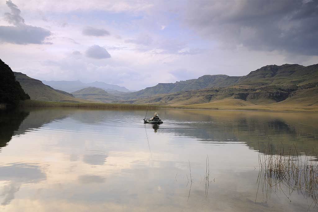 A kayak fisherman explores a lake among the mountains in South Africa