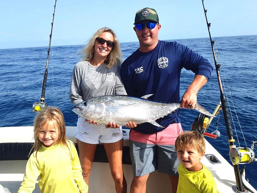 A photo of a family, a mom, a dad, and two kids, standing on a charter fishing boat around Tuna they caught during an angling trip in Mexico