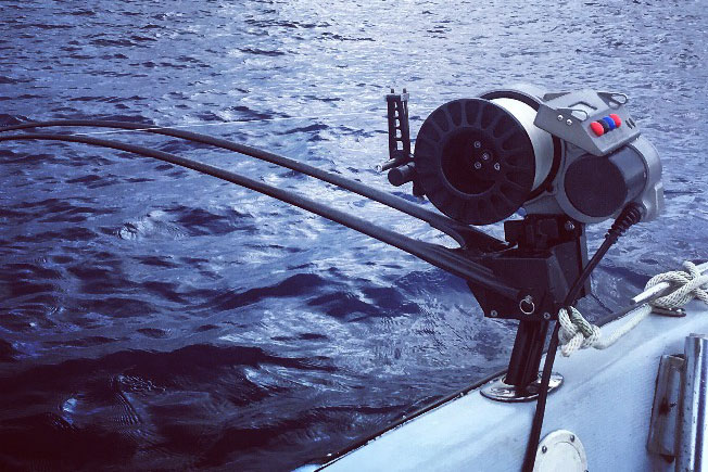 A deep-dropping rod hangs off the side of a fishing boat offshore from Cancún