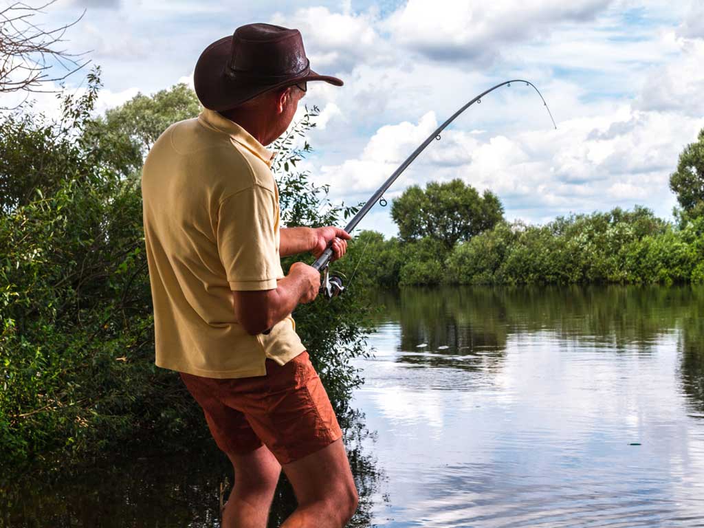 An angler reeling in a fish from shore.