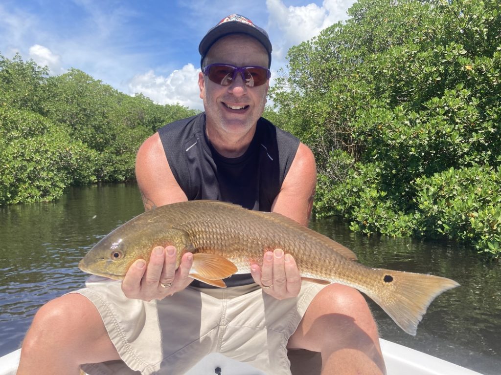 a smiling angler holding a Redfish Captain Mike&rsquo;s Back Bay Charters in Cape Coral, FL