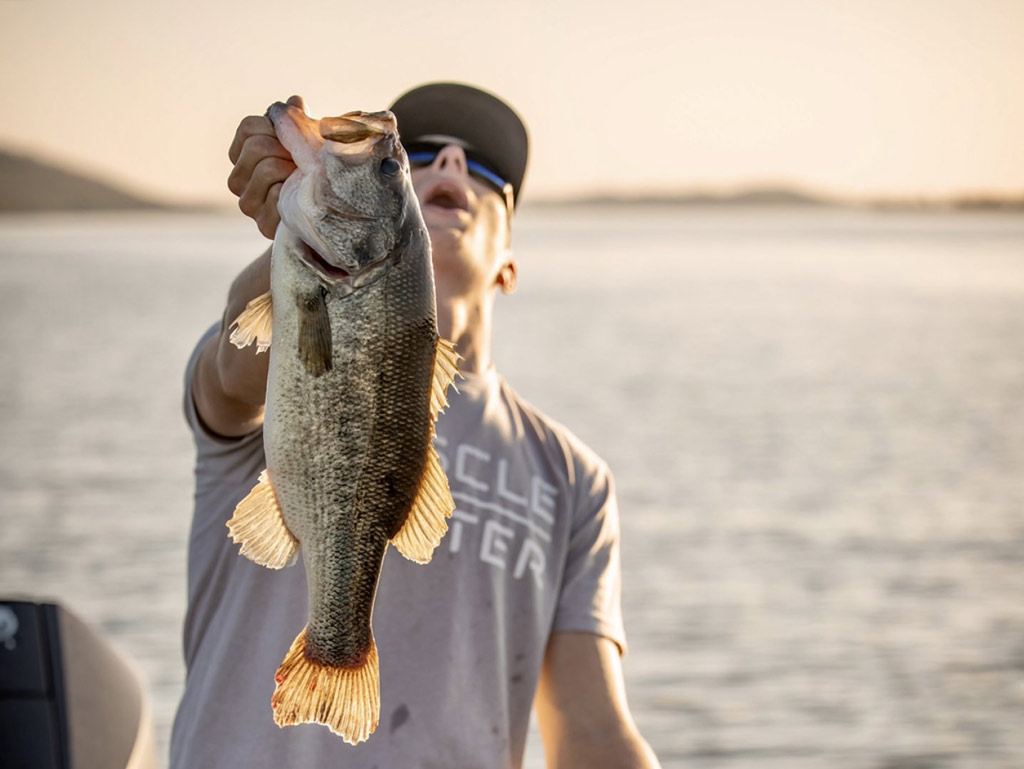 A happy angler holding a sizeable Largemouth Bass that he caught fishing on Lake Guntersville, Alabama.