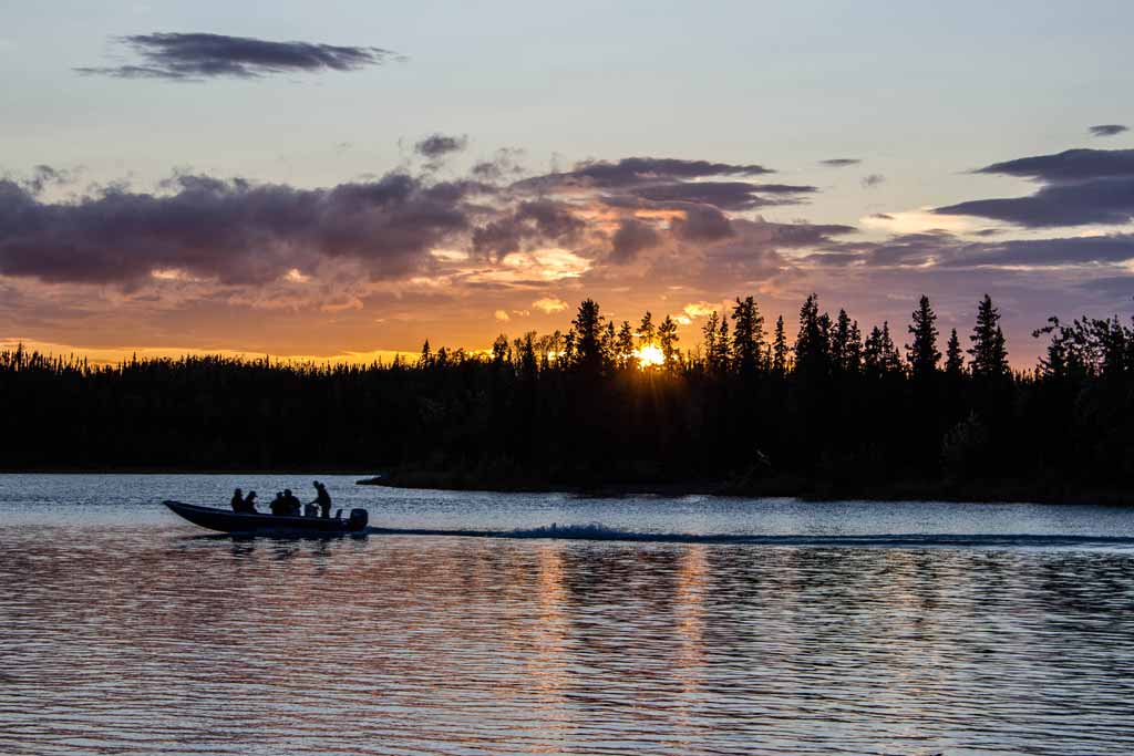 Anglers riding on a boat on the Kenai River at sunset