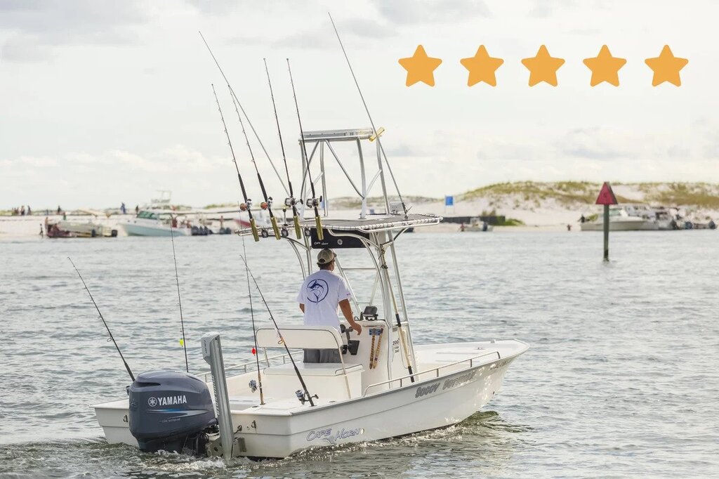 A photo of a captain taken from behind while he is steering his charter boat toward the shore and marina