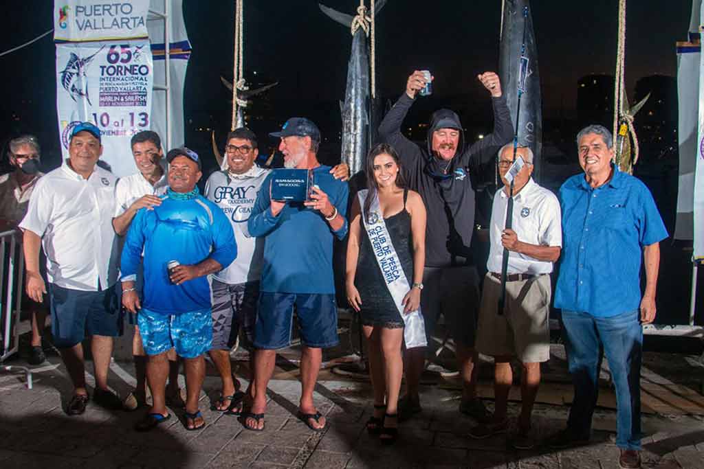 A winning fishing crew photographed on a dock with their catch behind them