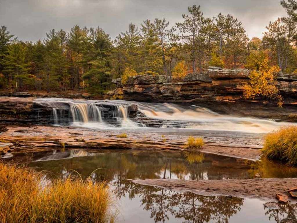 A lovely fall landscape in Minnesota showing a waterfall and surrounding foliage