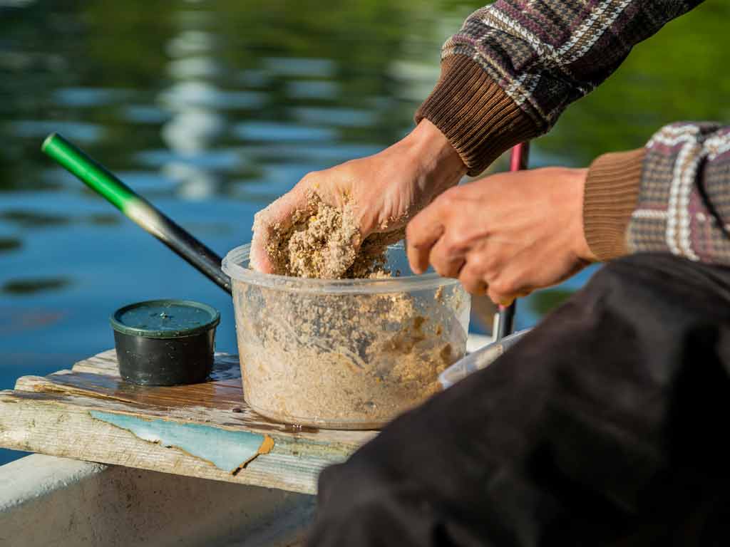 A close view of an angler’s hands while he is preparing chum for luring fish