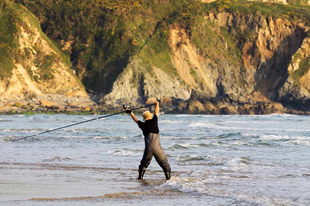 A fisherman wading in the surf, in the middle of surf casting