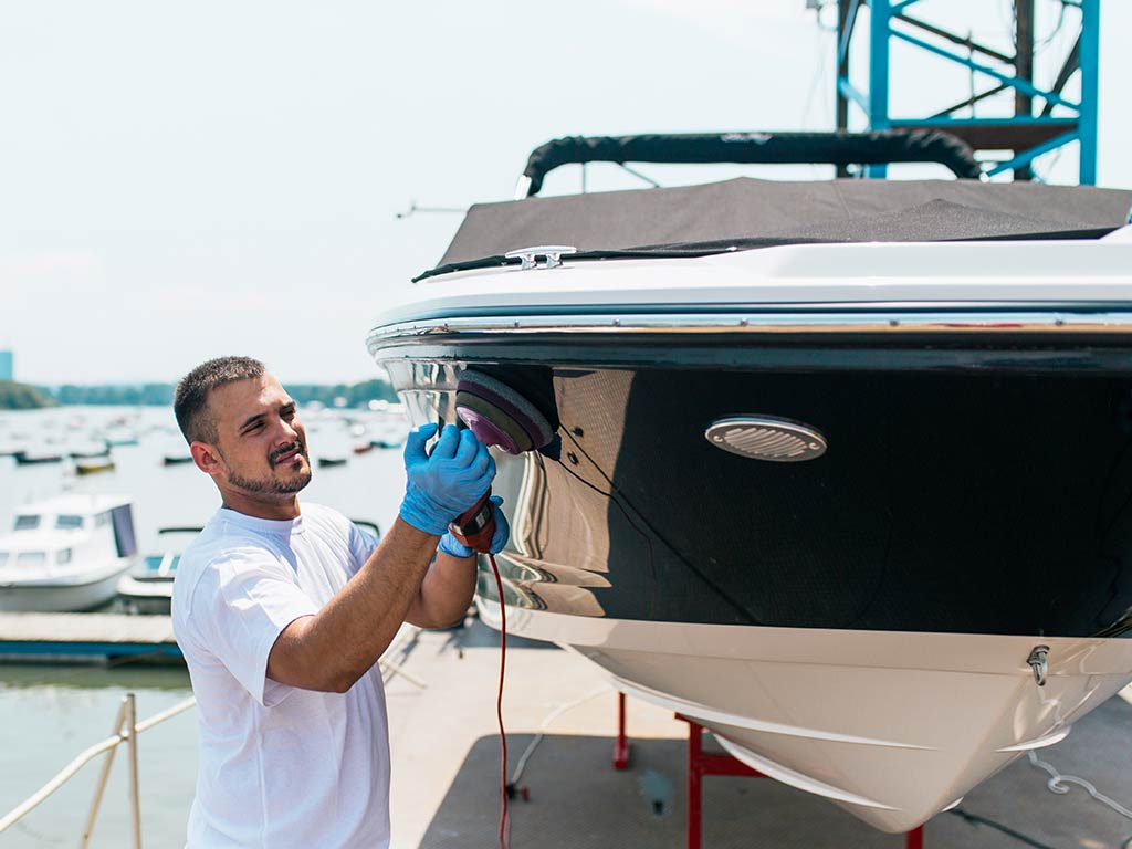 A man polishing his boat on a sunny day.