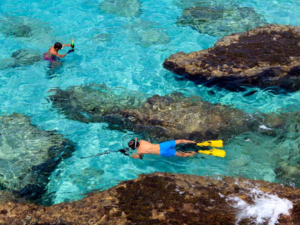 A bird's eye view of a child spearfishing while his friend is snorkeling nearshore 