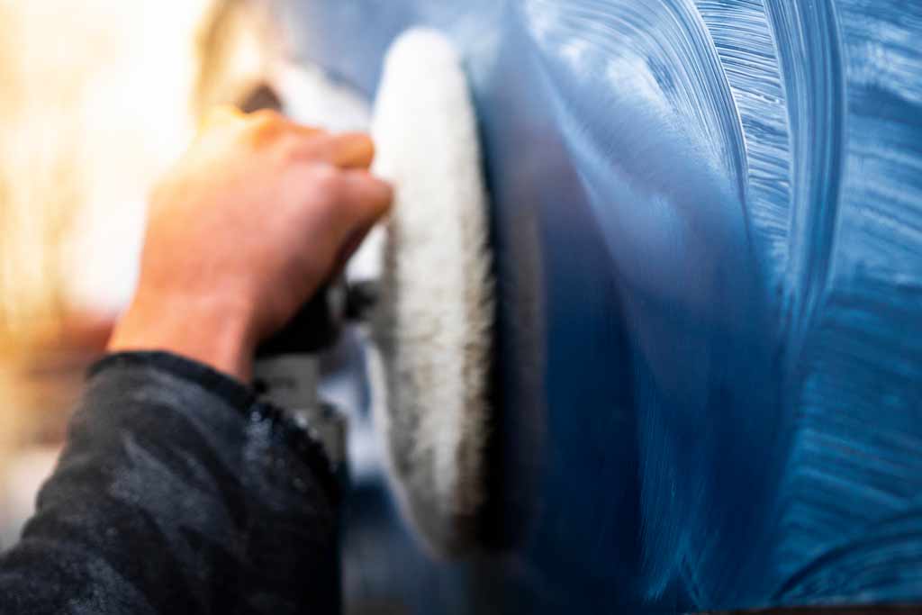 A close-up of a boat hull being waxed