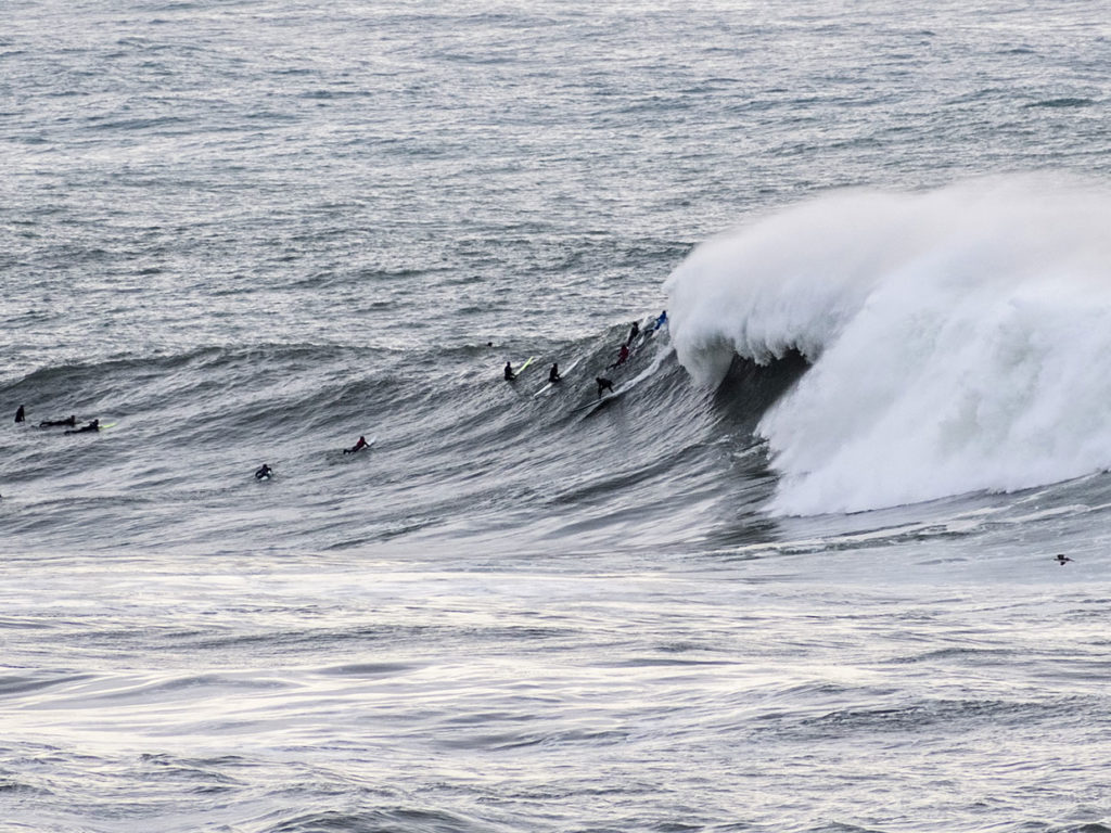 Surfers take on the waves at Mavericks Beach, CA