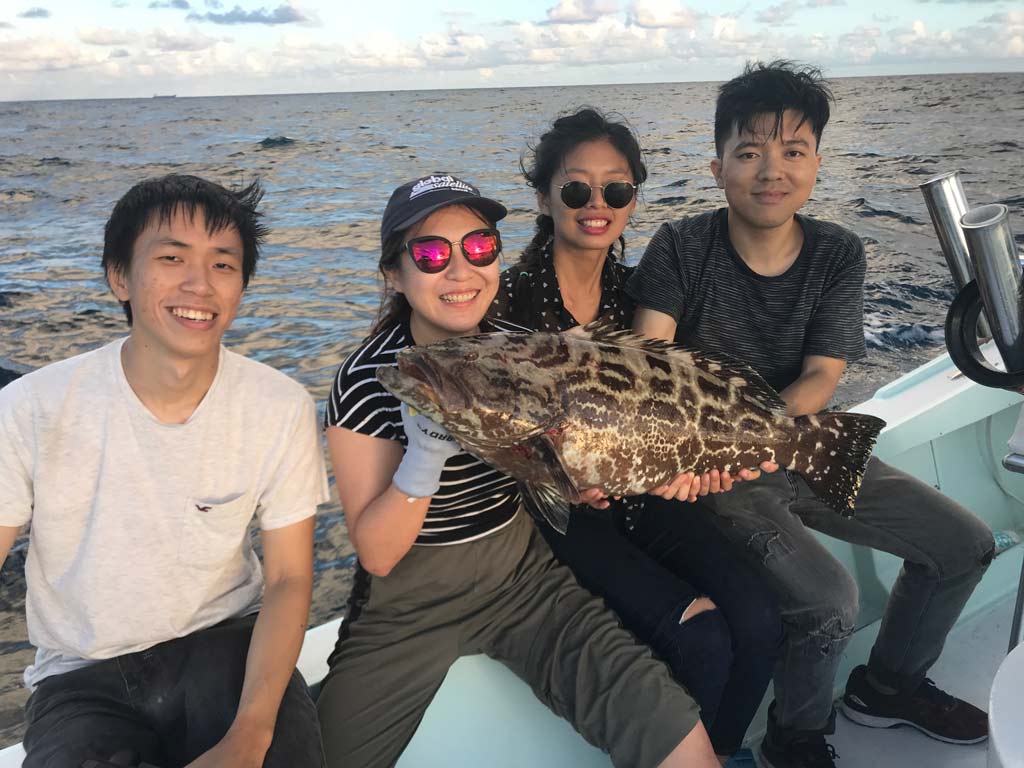 A group of anglers posing with a Black Grouper caught while party boat fishing in Fort Lauderdale.