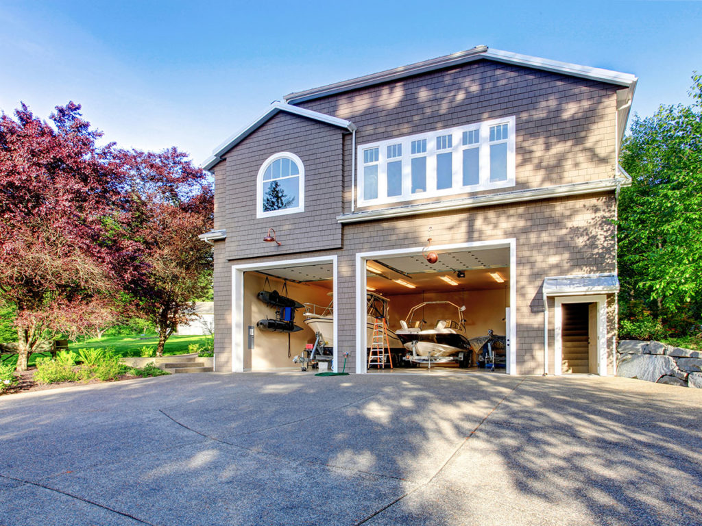 A house with two large garages, one of which has a boat inside