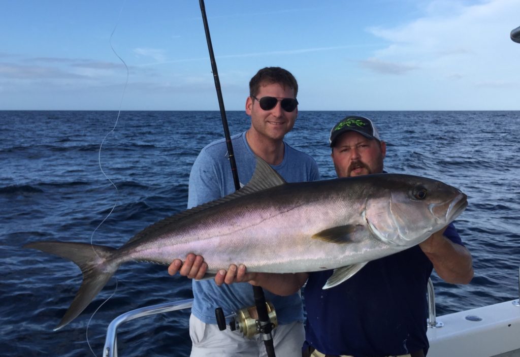 Two anglers holding an Amberjack caught while fishing offshore in Naples, FL