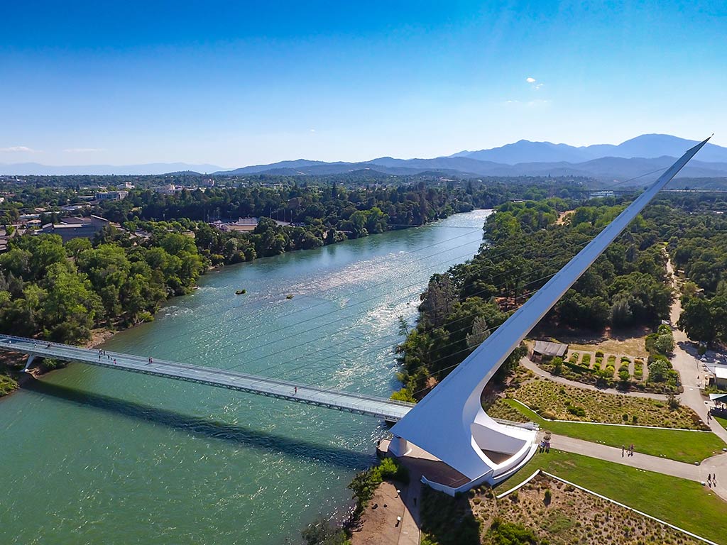 An aerial view of the Sundial Bridge at Redding, CA on the Fourth of July, with a pair of fishing boats in the background.