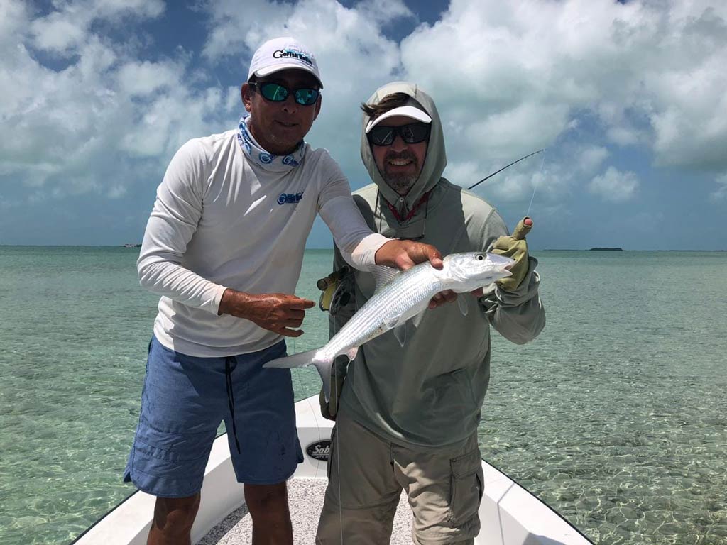 A photo featuring two anglers while standing on a charter fishing boat with Bonefish caught while fishing with GoFish Belize