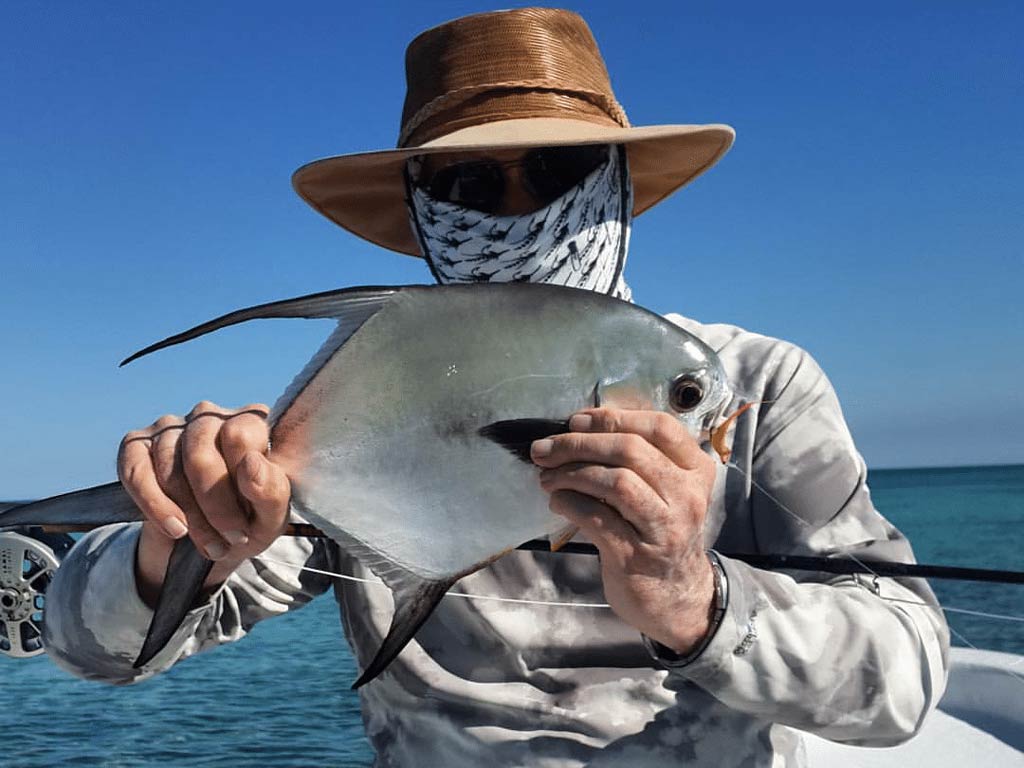 An angler holding a freshly caught Permit, fishing with Nano Guerrero, Belize