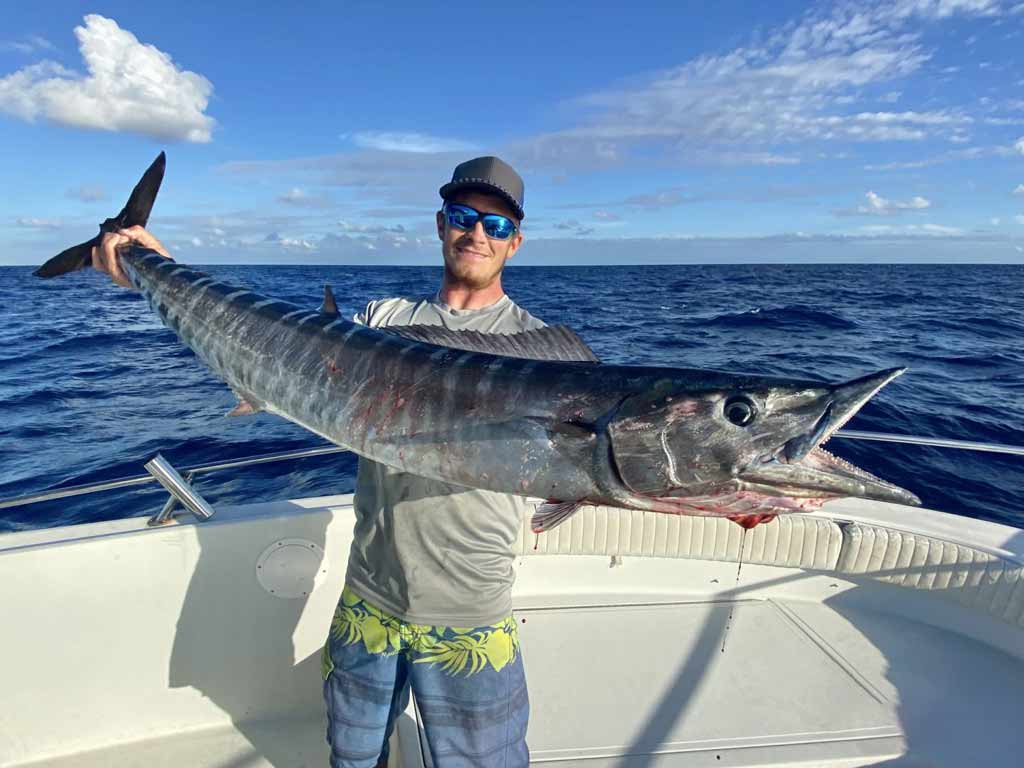 An angler holding a big Wahoo with both hands caught while deep sea fishing in Islamorada