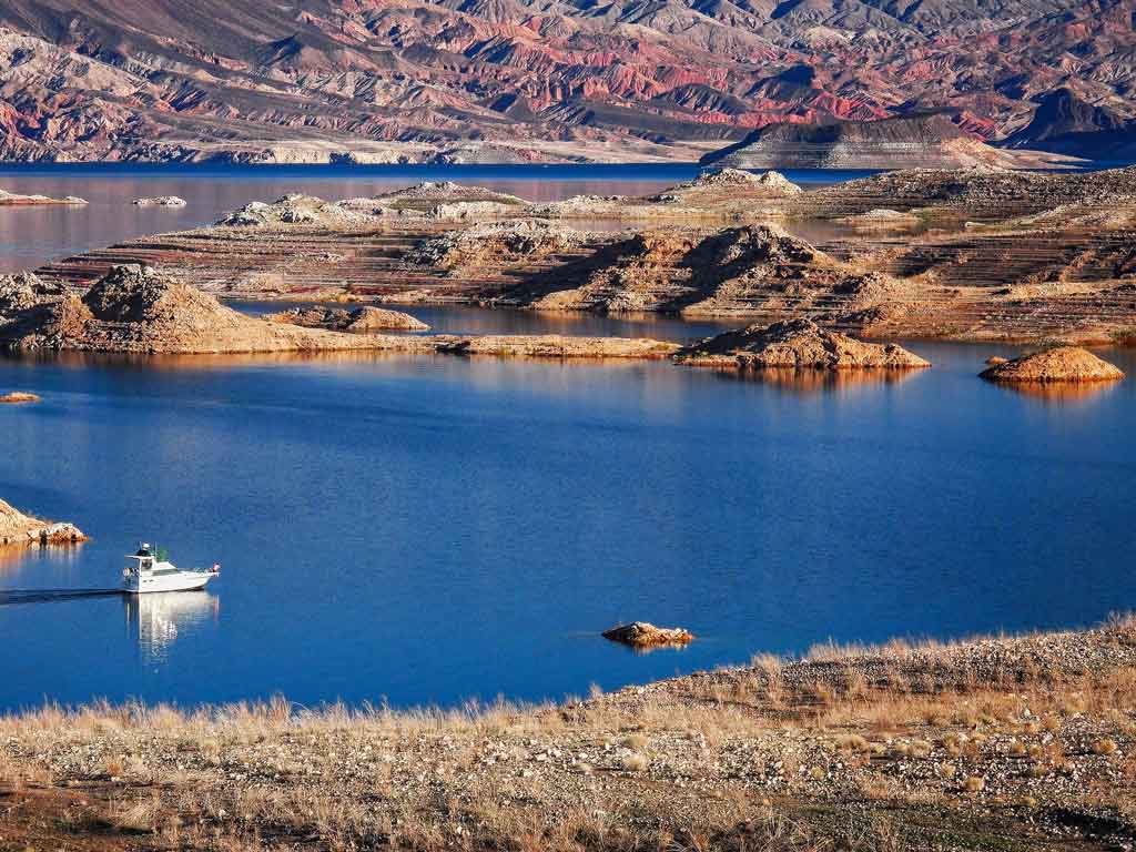 A photo of Lake Mead with a boat cruising on it on a sunny day.