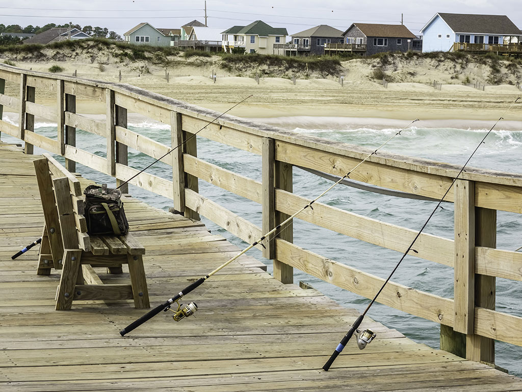 A photo of three rods lined up against the side of a fishing pier in North Carolina on a cloudy day