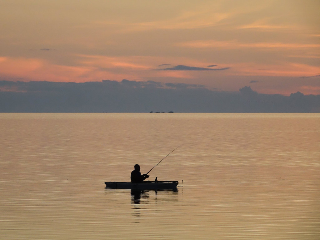 A photo of a kayak angler fishing in Fernandina Beach at sunset.