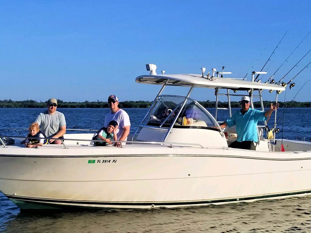 A side view of a charter boat in the shallows with a captain and group of anglers aboard