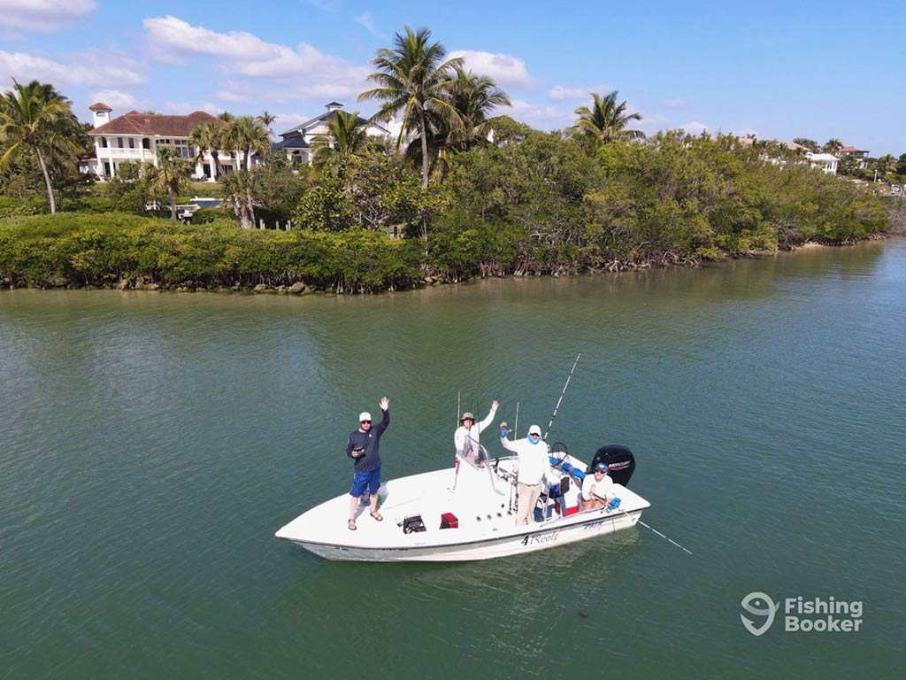 An aerial view looking towards a small boat on the inshore waters of Jupiter, FL, on a clear day as the anglers aboard wave towards the camera