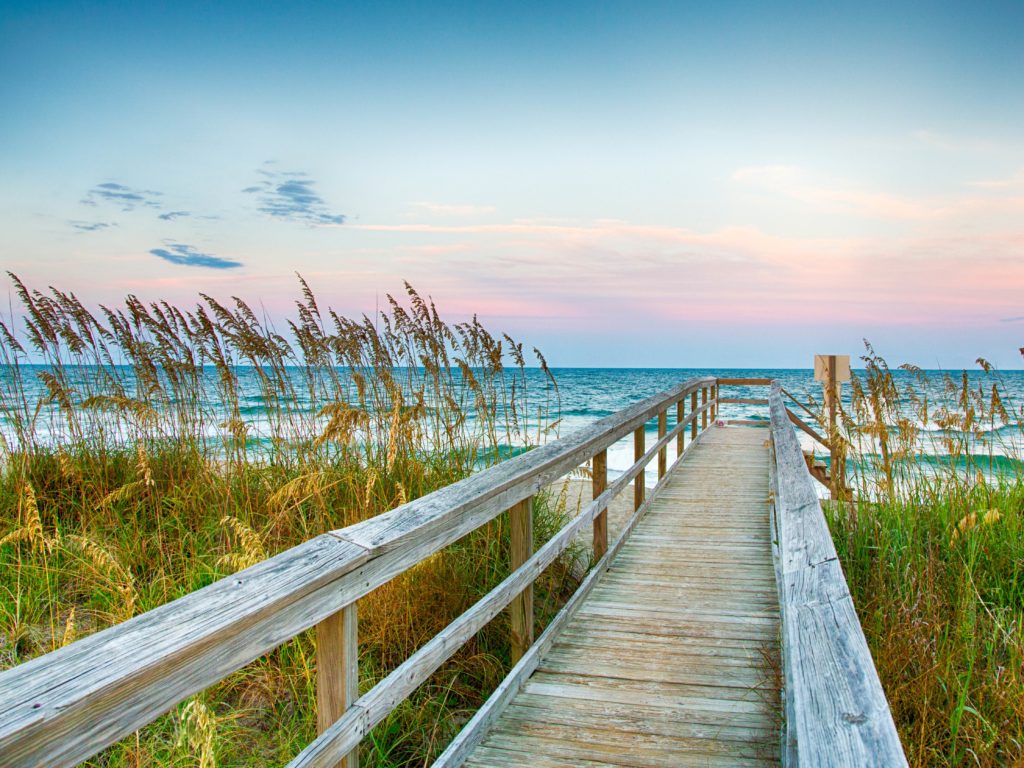 A view of Kure Beach in North Carolina with pink and light blue sky