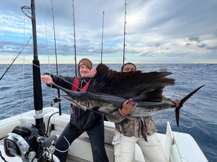 A picture showing two male anglers holding a Sailfish while on a charter fishing boat in Folly Beach, near Charleston, SC