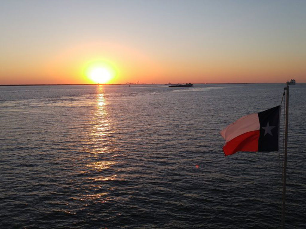 Sunset over Galveston Bay, Texas, picture taken from a boat with a Texan flag.