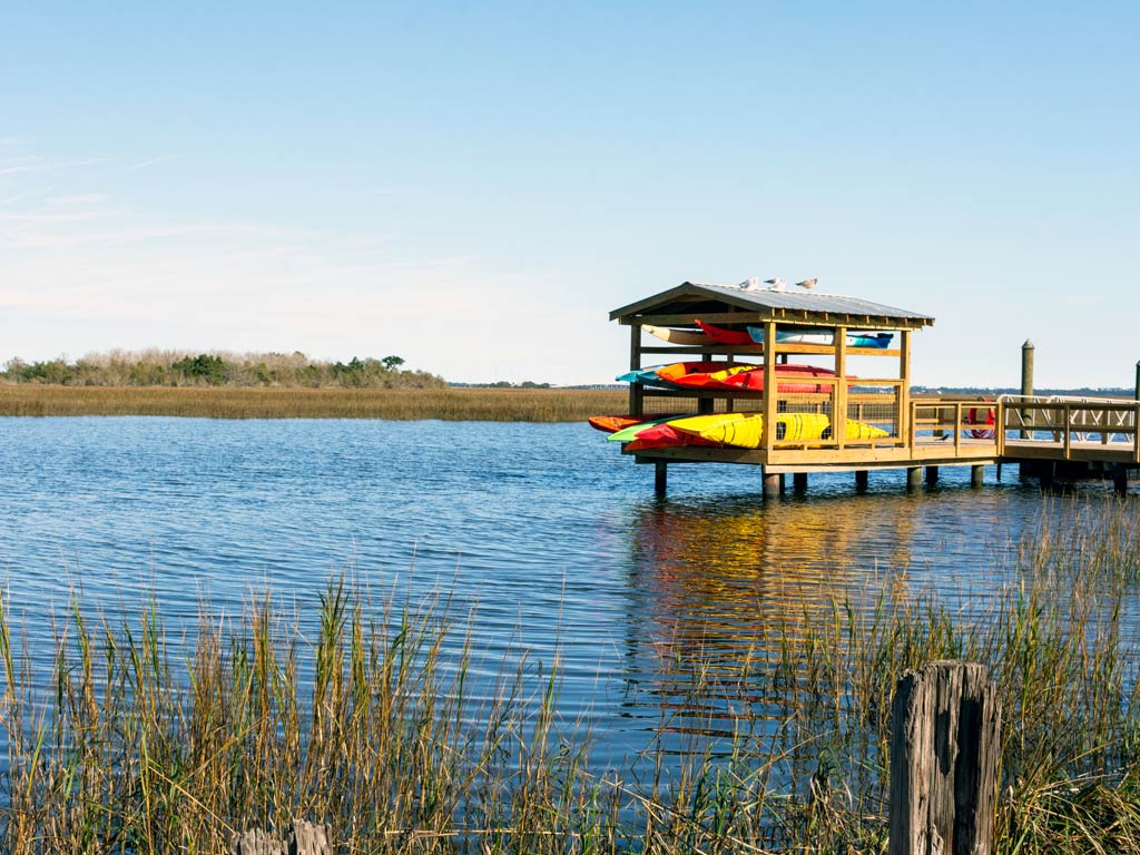 A photo featuring Georgia’s marshes and wetlands with a wooden structure  fully loaded with kayaks for kayaking or kayak fishing