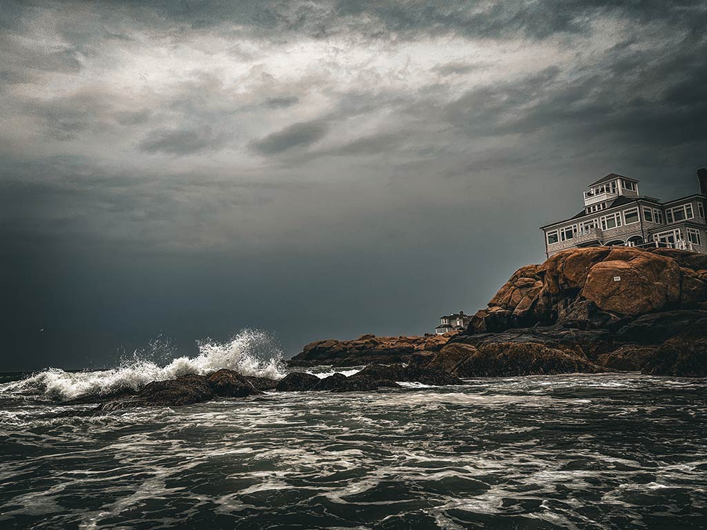 A view across the sea of choppy waters crashing into a rock in Gloucester, MA on a stormy day