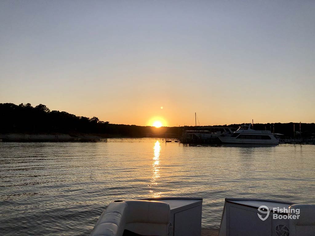 A view out from the back of a Kingston, OK, fishing charter towards the sun setting in the distance on a clear day